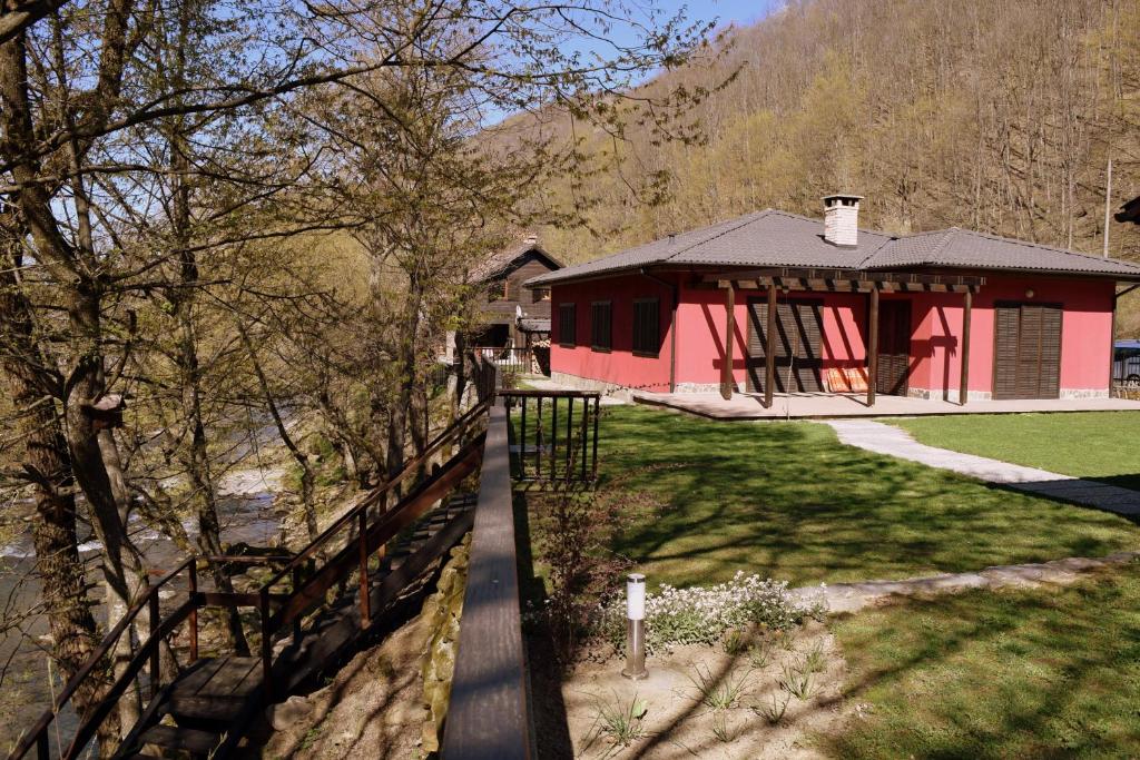 una casa roja con una valla al lado de un patio en Boyana Vacation Houses, en Cherni Vit