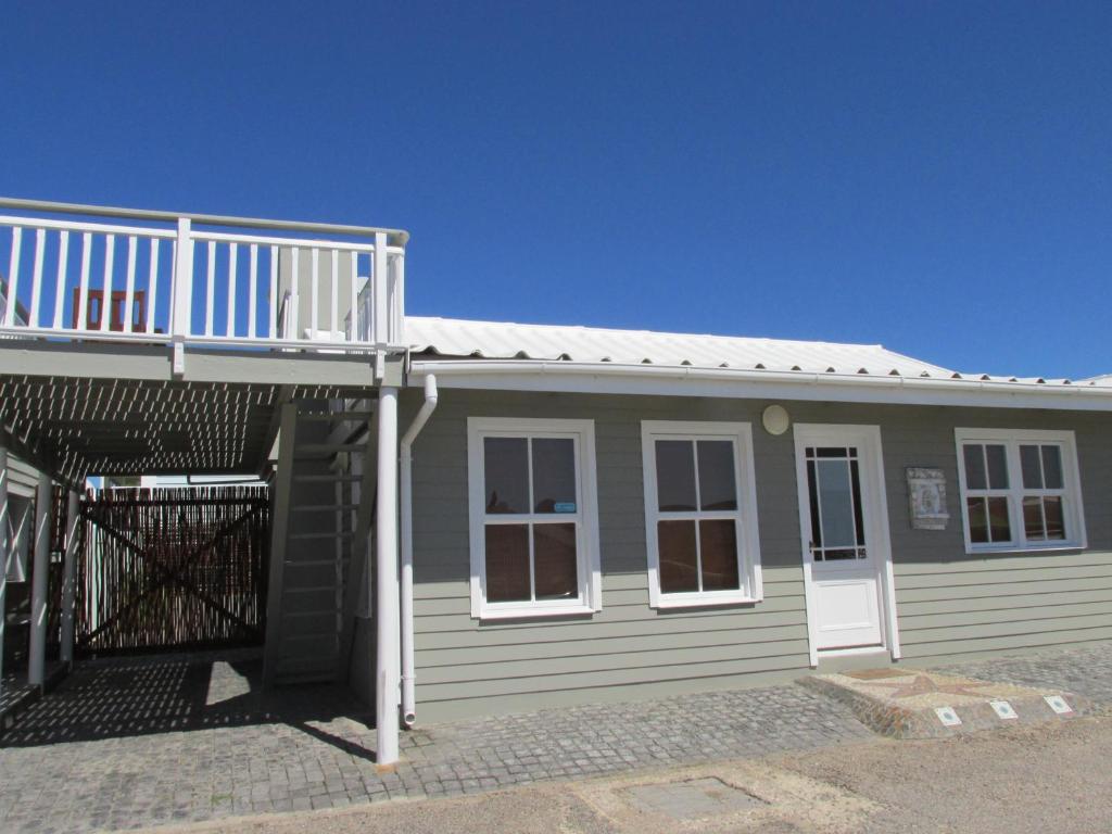 a small house with a deck and a balcony at Point Village Accommodation -Linky's House in Mossel Bay