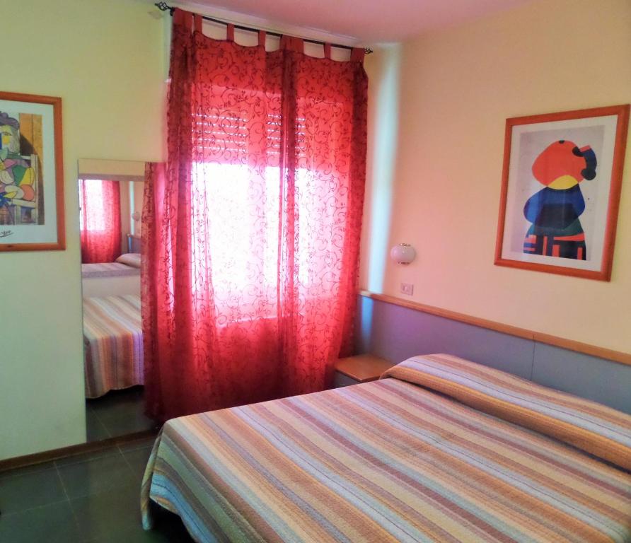 a bedroom with two beds and a red curtain at Hotel Lucerna in Arma di Taggia