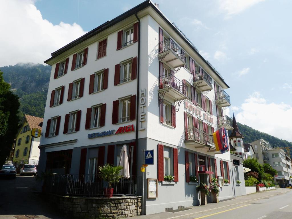 a white building with red windows and balconies on a street at Hotel Rigi Vitznau in Vitznau