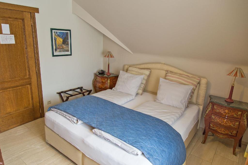 a bedroom with a bed with a blue blanket on it at Hotel Wilgenhof in Maaseik