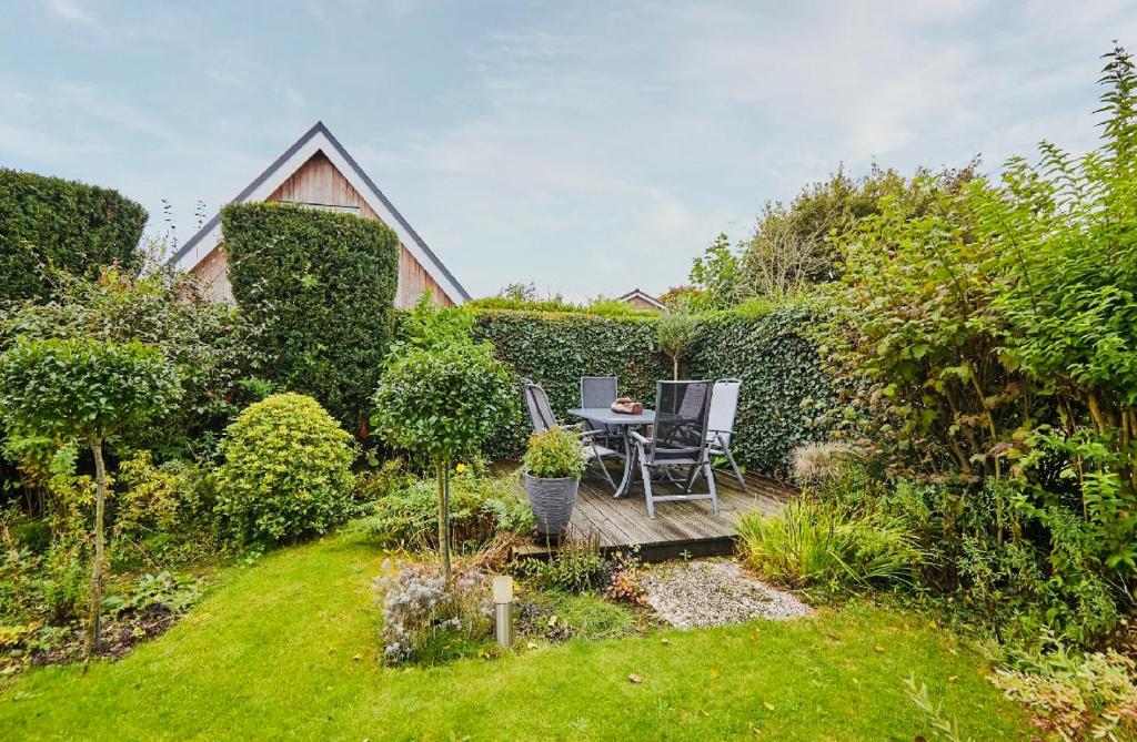 a garden with a table and chairs on a wooden deck at Beleef Noordwijk strandhuisje in Noordwijk aan Zee