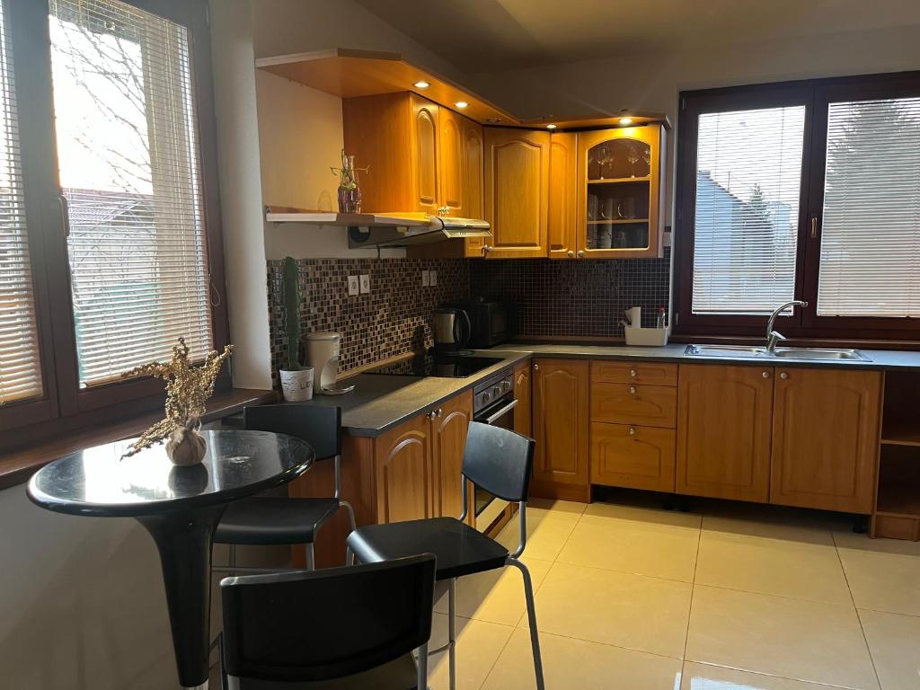 a kitchen with wooden cabinets and a table with chairs at Dom pri kúpalisku Thermalpark na Malotejedskej in Dunajská Streda
