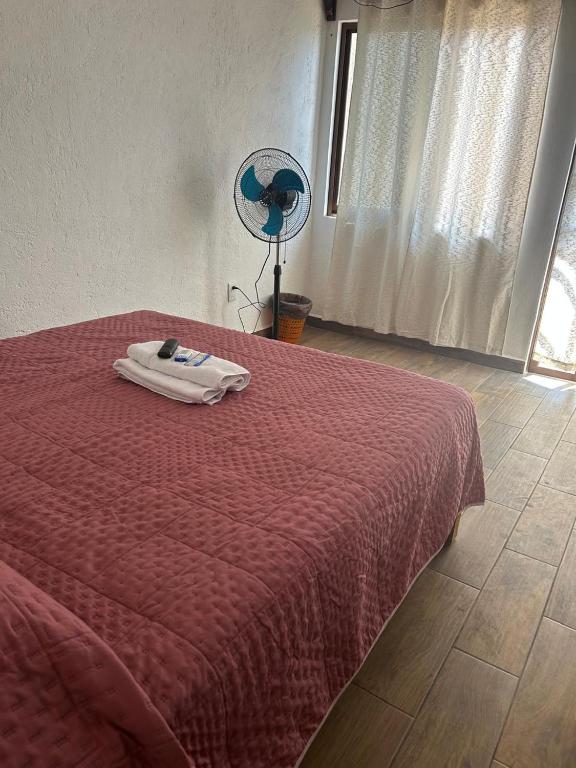 a bedroom with a bed with a red blanket and a fan at casa regina in Tepoztlán