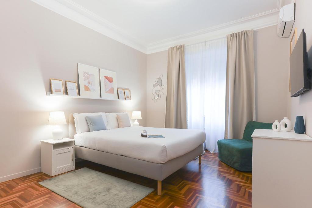 ローマにあるPiramide Deluxe Apartmentのベッドルーム(白いベッド1台、緑の椅子付)