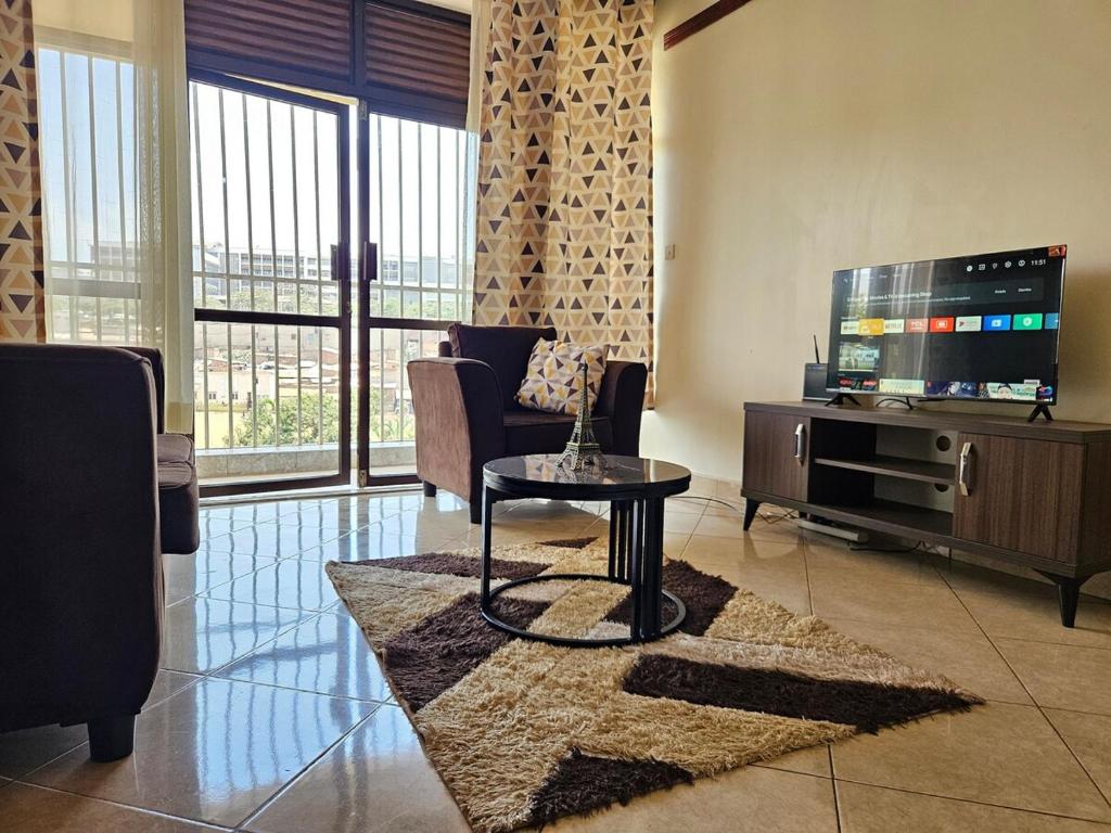 Una sala de estar con televisión y una mesa de café. en NL residence - Kampala, en Kampala