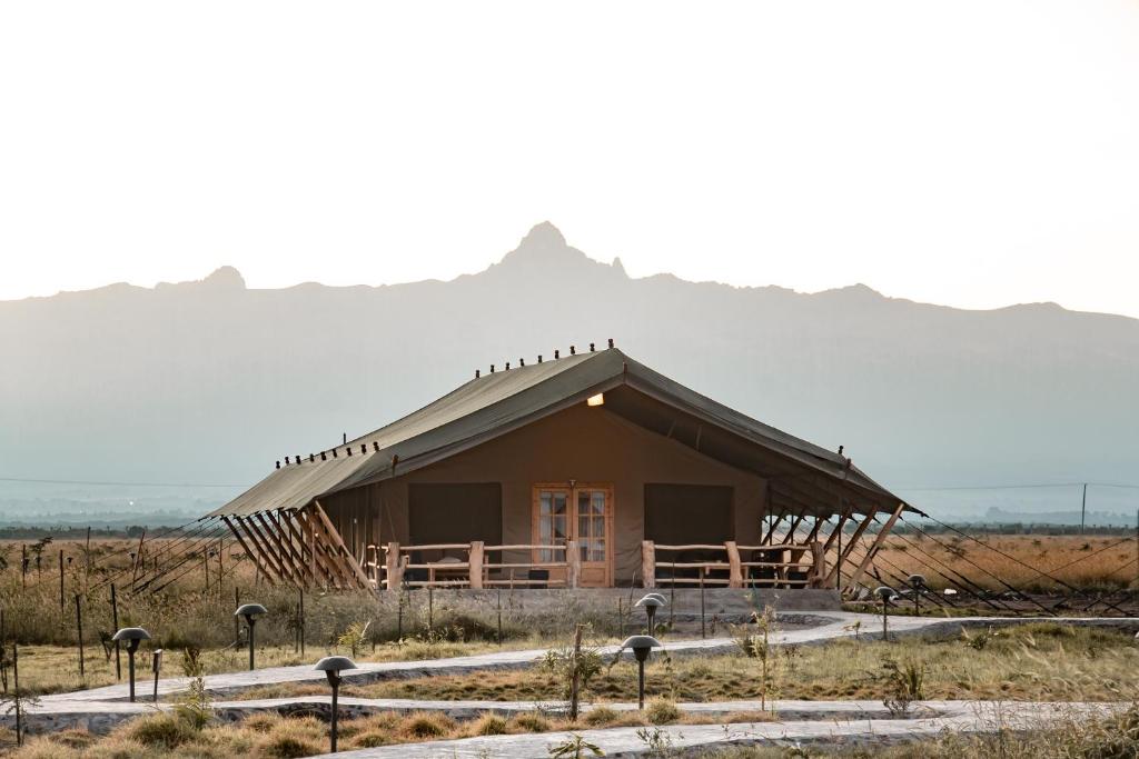 a small building in a field with a mountain in the background at MAISHA SWEETWATERS CAMP in Ol Pejeta Conservancy