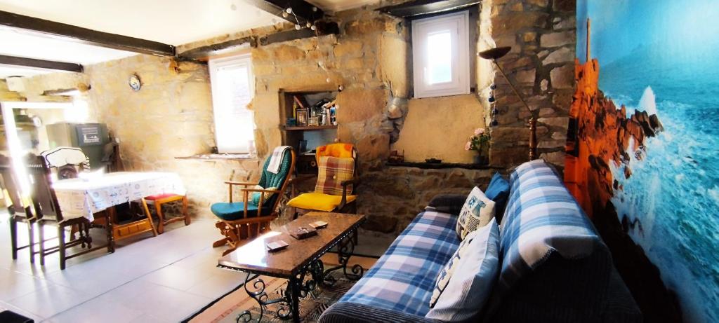 a living room with a couch and a table at Coeur de granit rose, meublé alliant le charme de l'authentique breton et du confort, classé 3 étoiles, à 5mn de 13 plages de la réputée cote de granit rose in Trégastel