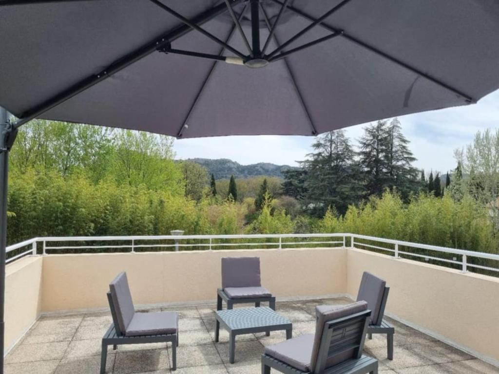 un patio avec des chaises, une table et un parasol dans l'établissement Appartement Le Petit Nid Cévenol, à Anduze