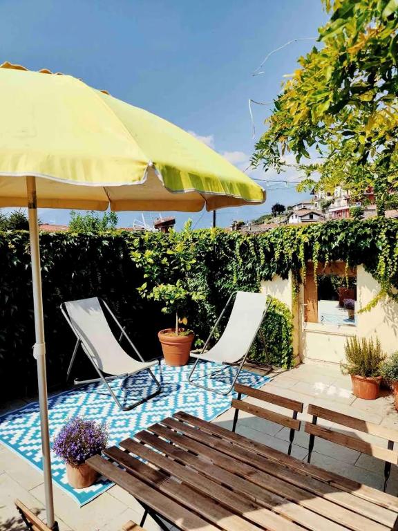 a patio with two chairs and an umbrella and a bench at Casalago in Domaso