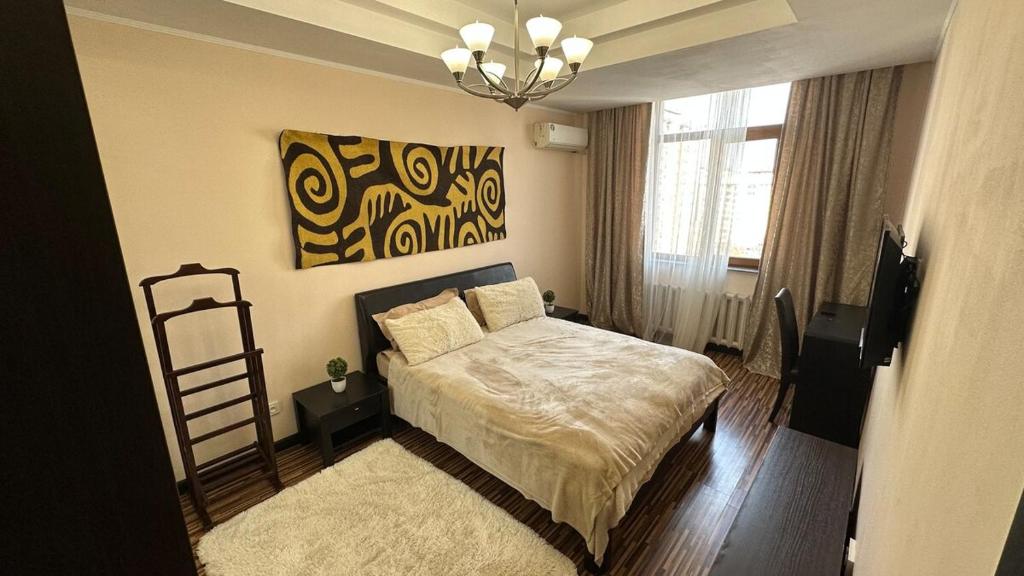 Un dormitorio con una cama y un cuadro en la pared. en Comfortable flat in center, en Bishkek