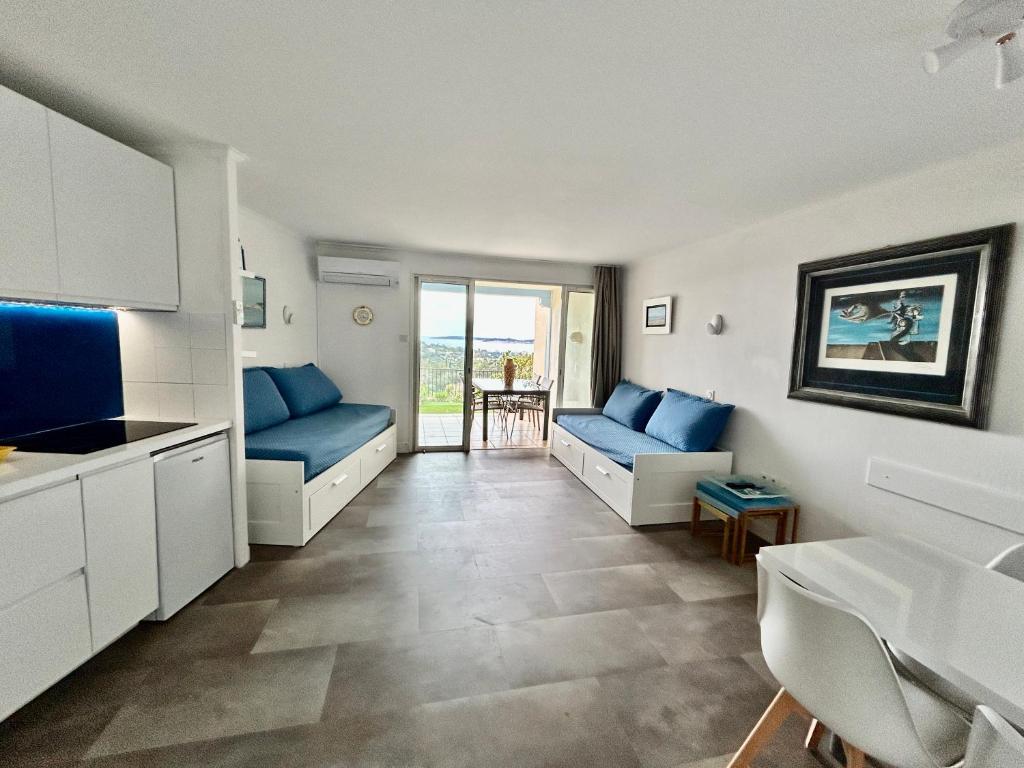 eine Küche und ein Wohnzimmer mit blauen Sofas und einem Tisch in der Unterkunft Les Restanques vue mer Capucines 1057 in Grimaud
