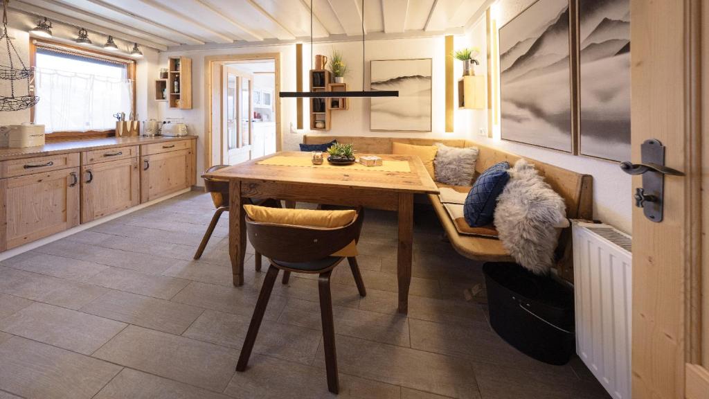 a kitchen with a wooden table and a couch at Kuschel Alpin Apartment & Traumblick Nockberge auf H1200m in Plessnitz