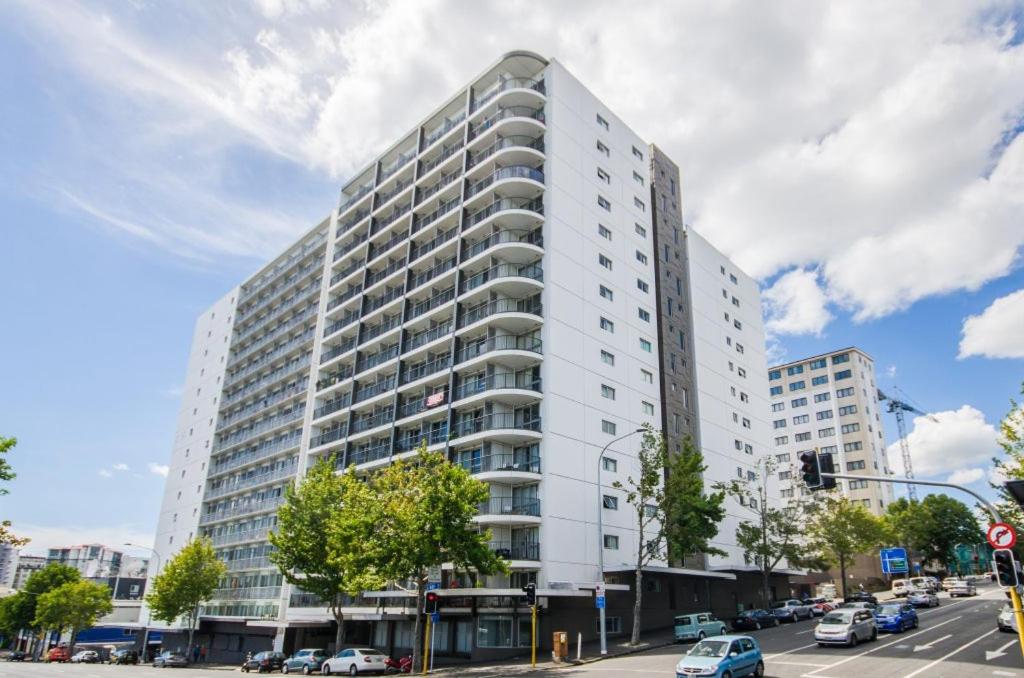 un edificio blanco alto en una calle de la ciudad con coches en aura 2 bedrooms 1 living room balcony goodView swiming pool, gym, en Auckland