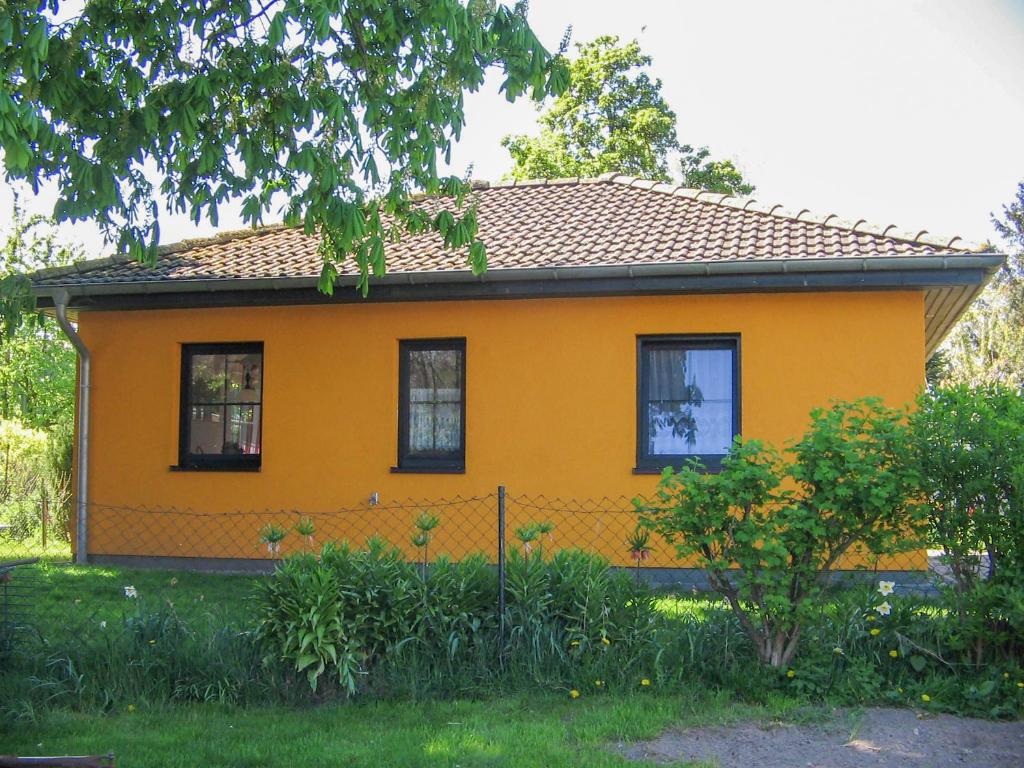 una casa amarilla con una valla delante en Ferienhaus Bohne, en Rubitz