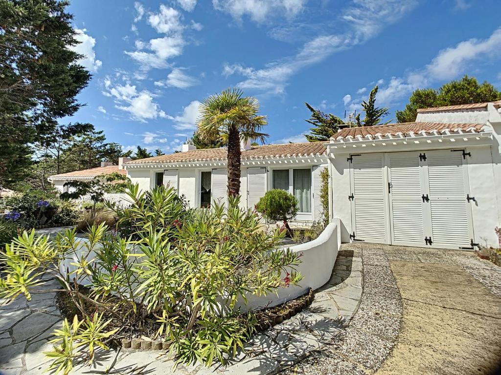 une maison blanche avec un palmier devant dans l'établissement Maison sur la dune à 100m de la plage, à La Guérinière