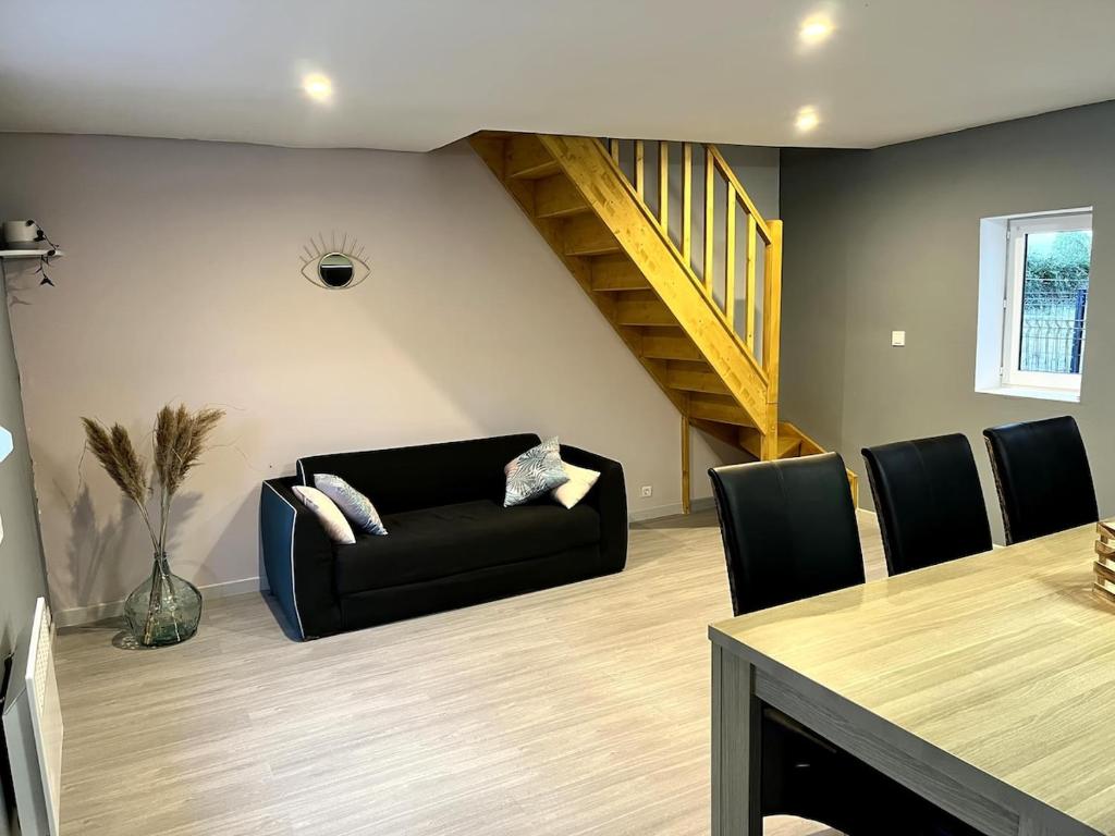 un salon avec un canapé noir et une table dans l'établissement La sérénité en baie de somme, à Béhen