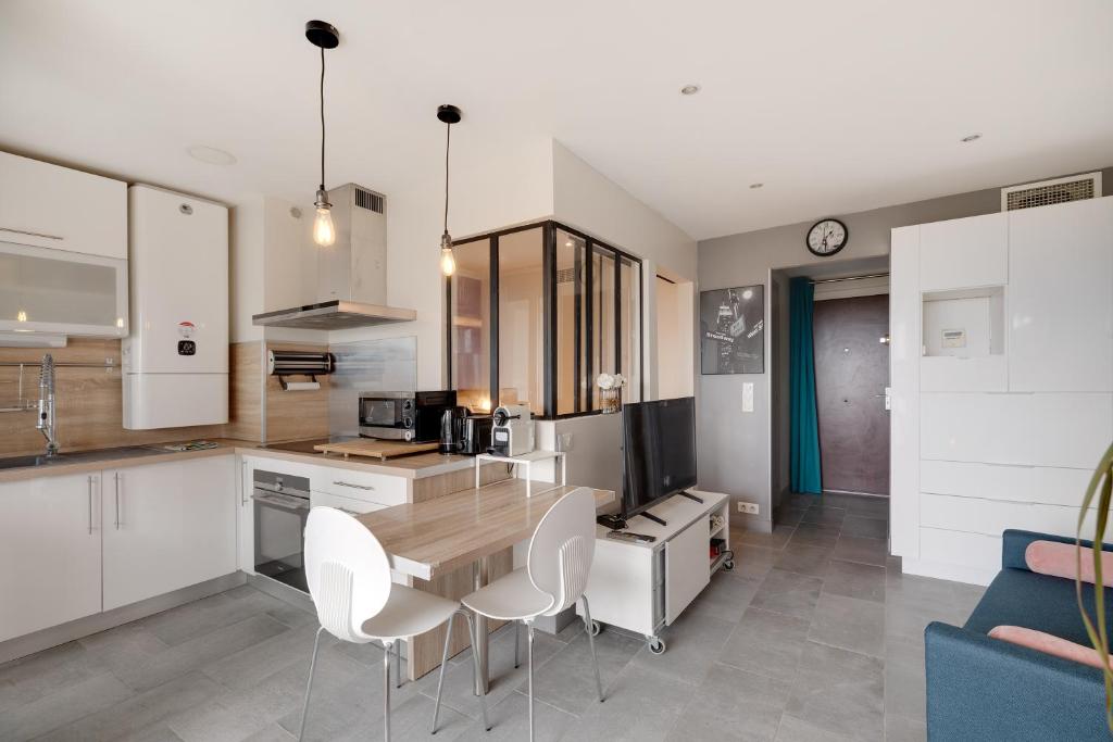 une cuisine avec une table en bois et des armoires blanches dans l'établissement Le soleil d'or , Piscine et Tennis, à Antibes