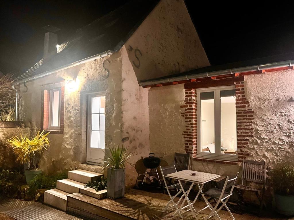 une maison avec une table et des chaises à l'extérieur la nuit dans l'établissement Charmante petite maison, à 5 mn de Blois, à Vineuil
