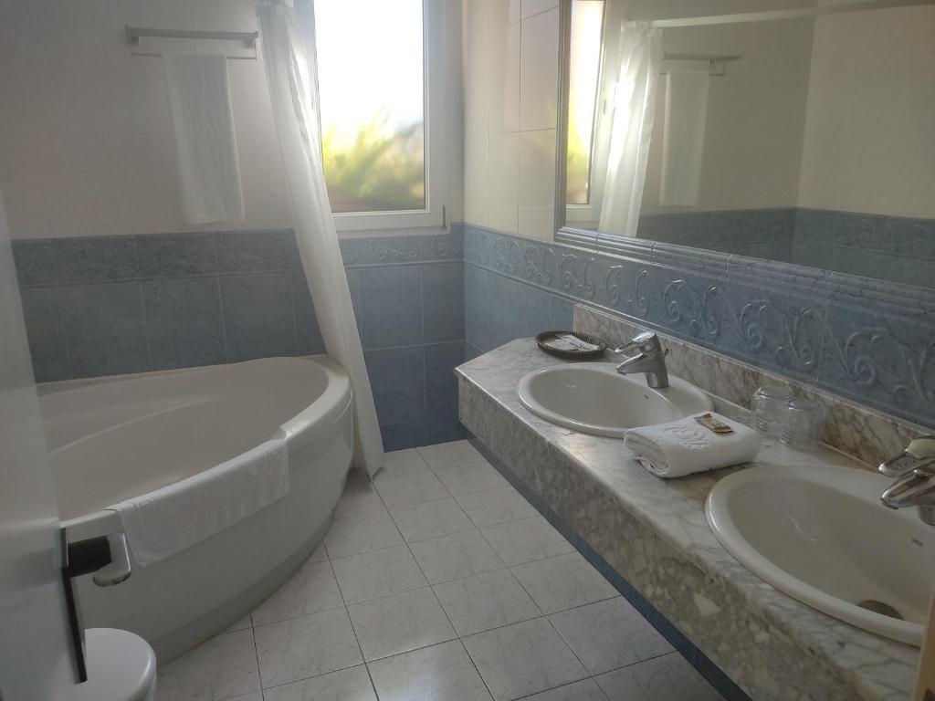 un bagno con due lavandini, una vasca e un WC di Habitación triple con bañera y terraza HOTEL SUITE MIOÑO a Castro-Urdiales