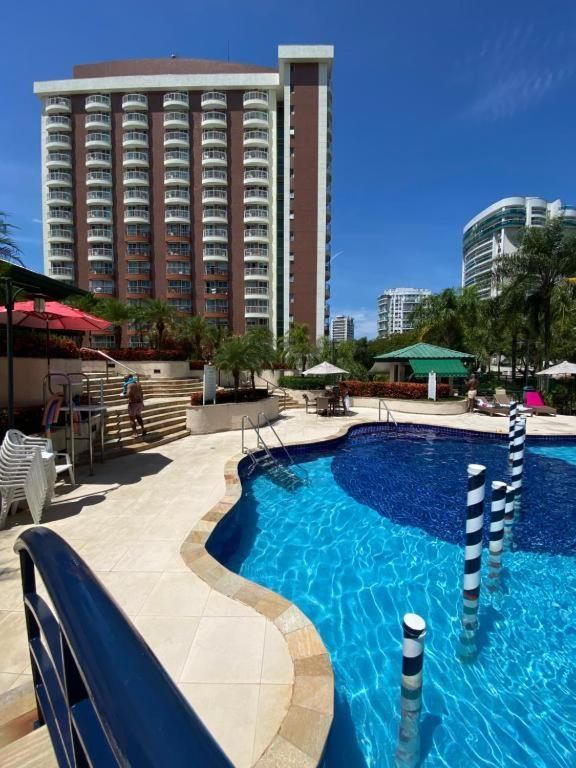 a swimming pool in front of a large building at Flat na Barra da Tijuca - Premium - Com Cozinha, Microondas, Estacionamento, Balsa para Praia, Academia, Muito lindo, Confortável e Aconchegante in Rio de Janeiro