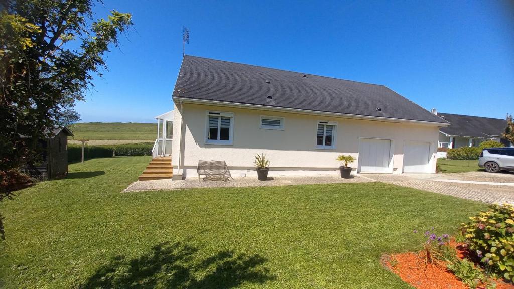 a white house with a porch and a yard at Chez MONIQUE in Sainte-Marguerite