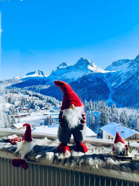three santa claus figurines sitting on a ledge with mountains at Ritschis Home in Arosa