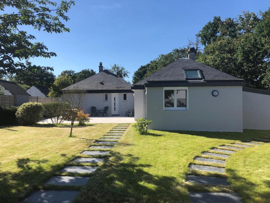 una pequeña casa blanca con un patio de césped en La Louisine séjours du samedi au samedi, en Séné