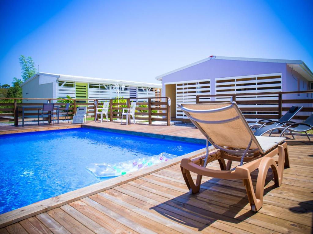 a chair sitting on a deck next to a swimming pool at Gîtes La Simonière & Cars in Saint-François