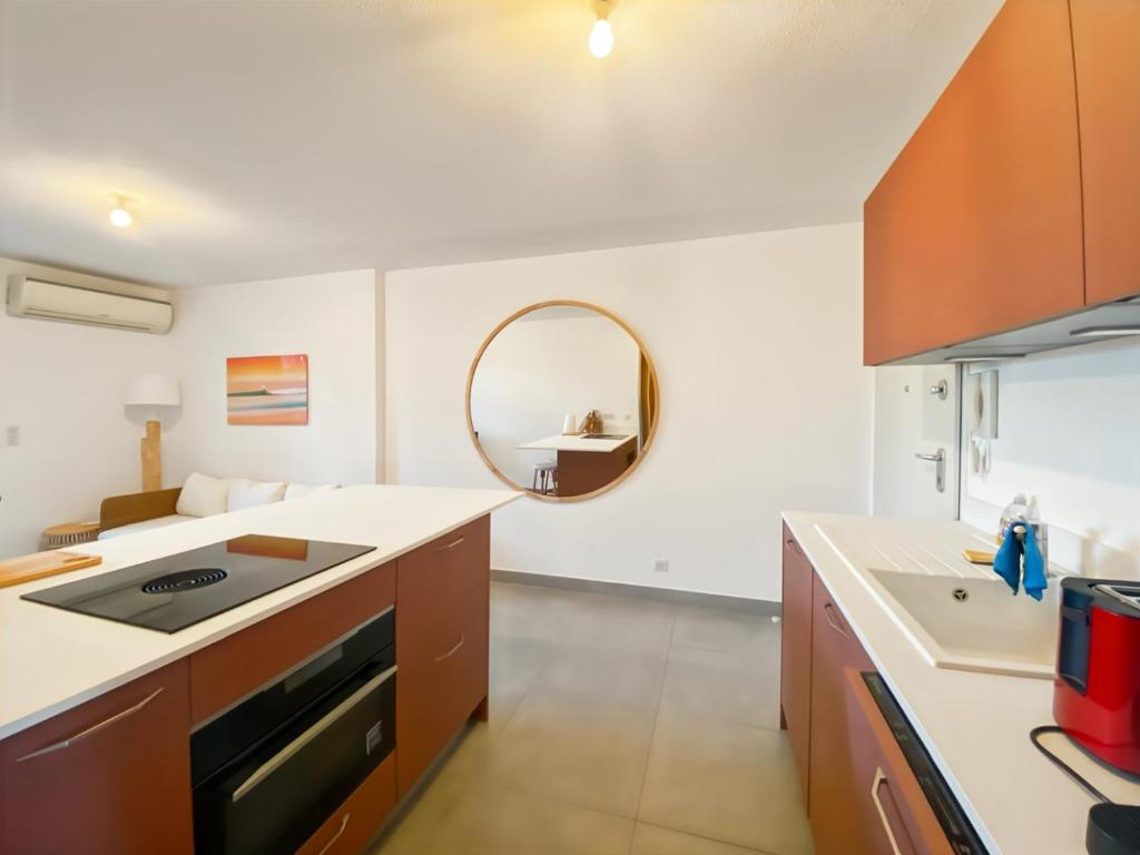 - une cuisine avec un évier et un miroir dans l'établissement Charmant T2 Ile Rousse, proche centre ville, à LʼÎle-Rousse