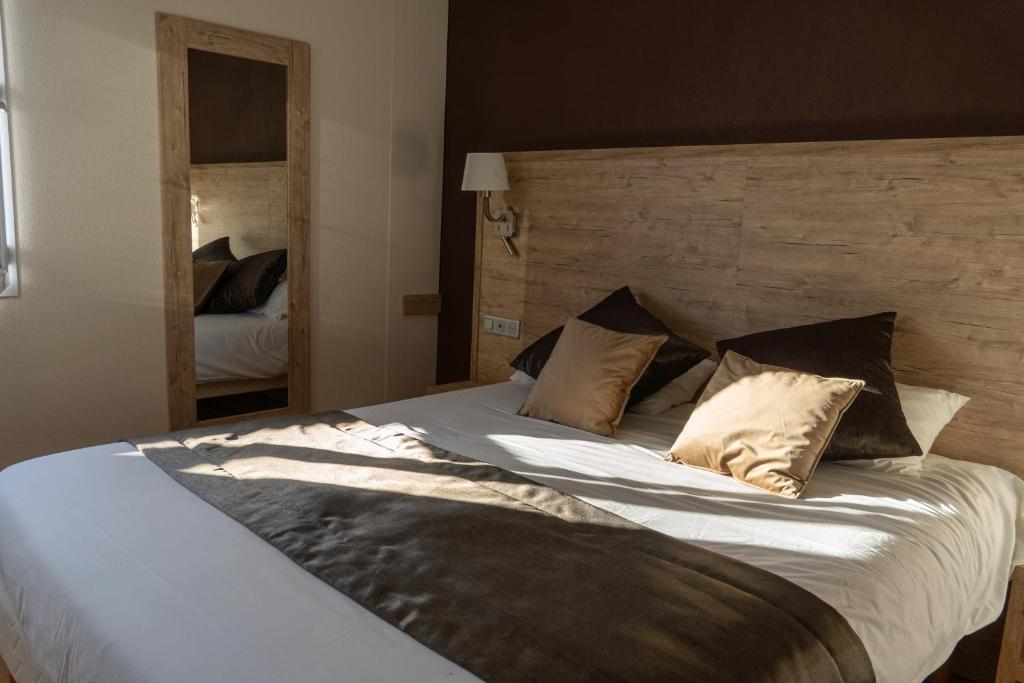 Un dormitorio con una cama grande con sábanas y almohadas blancas. en Cit&#39;Hotel Restaurant du Bowling de Millau, en Millau