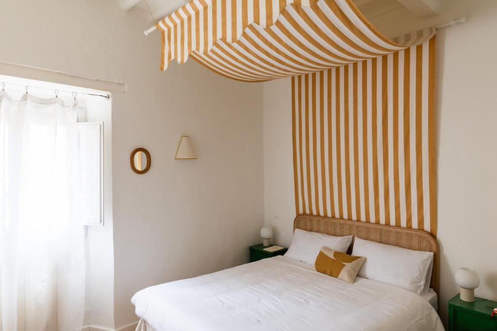 1 dormitorio con 1 cama con pared a rayas en Inn Oltremare - appartamento di design a un passo dal centro e dal mare, en Livorno