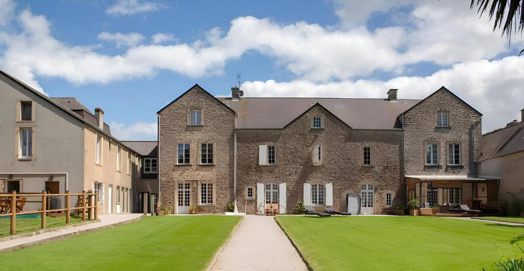 un grand bâtiment en briques avec une pelouse verte dans l'établissement La villa des 3, à Tamerville
