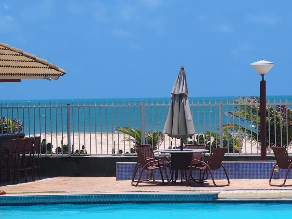 a patio with a table and umbrella next to a pool at Terra mares Porto das dunas in Aquiraz