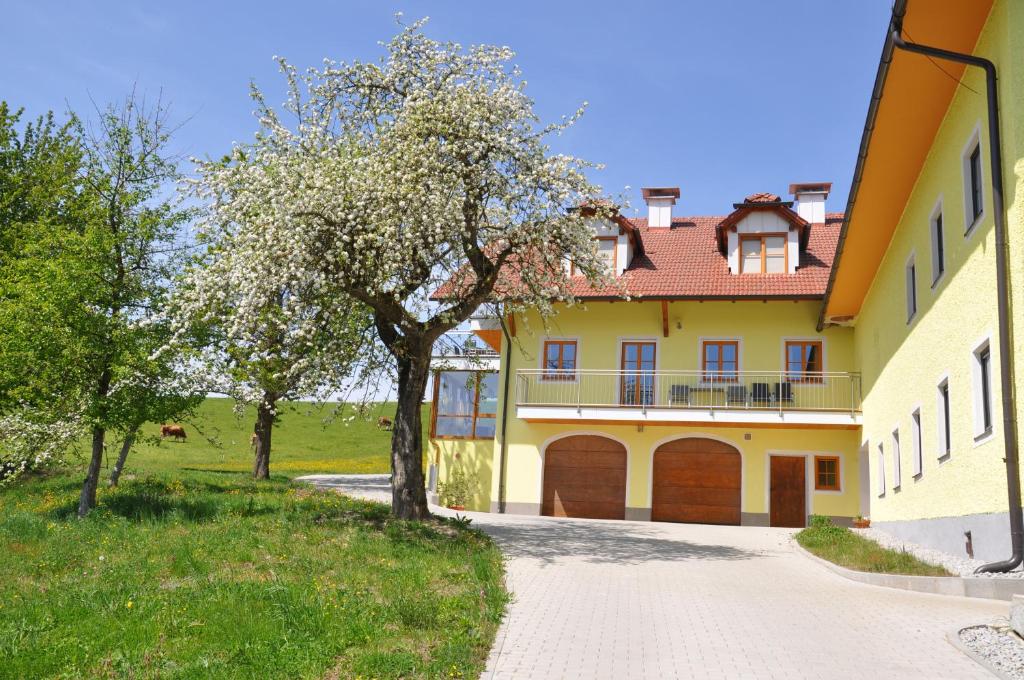 żółty dom z drzewem i podjazdem w obiekcie Ferienwohnung Mayrhofer w mieście Hofkirchen im Mühlkreise