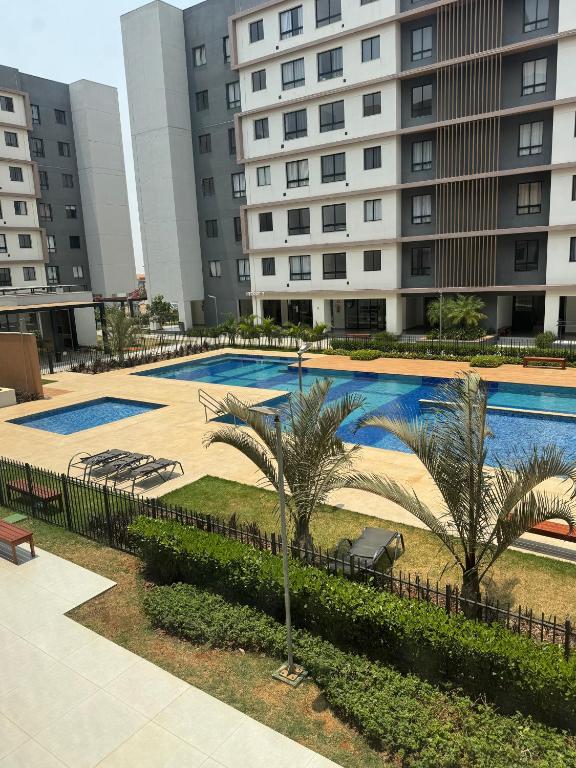 a swimming pool with palm trees in front of buildings at Apto 202, Torre 1 in Lucas do Rio Verde