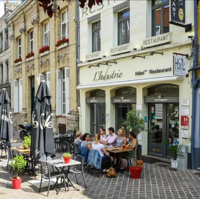 a group of people sitting at tables outside a restaurant at Hôtel Restaurant L'Industrie in Saint-Omer