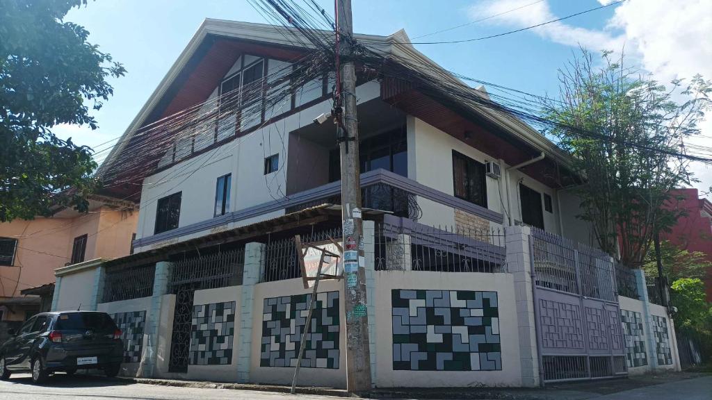 a white building with a fence in front of it at Spacious 3-Floor 6-BR Home, Pool, BBQ, KTV, WIFI in Davao City