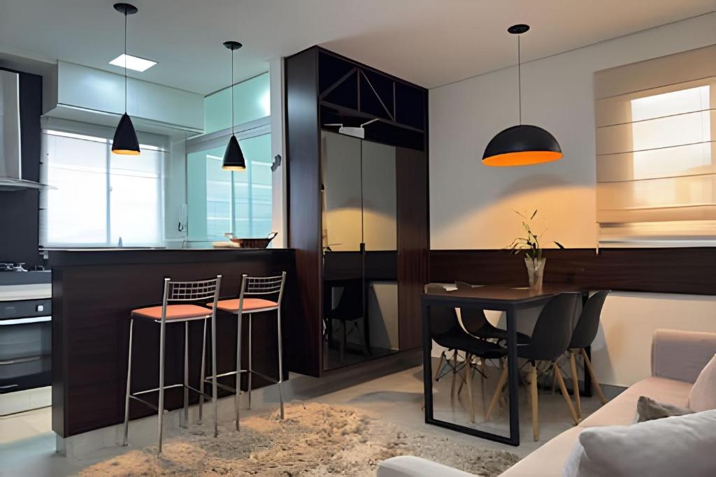 eine Küche mit einer Bar mit Hockern und einem Tisch in der Unterkunft Conforto e Praticidade em Araxá in Araxá