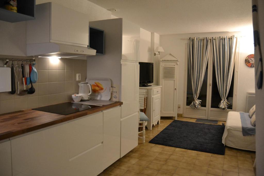 une cuisine avec des armoires blanches et un salon dans l'établissement Maison à l'Océan, à Batz-sur-Mer