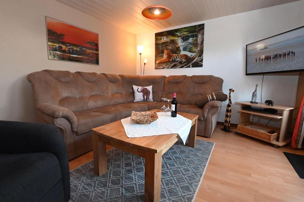 een woonkamer met een bruine bank en een tafel bij Haus-Karin-Ferienwohnung-1 in Büsum