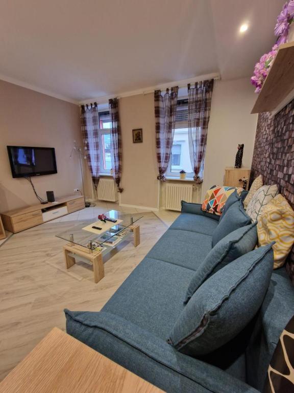 Una sala de estar con un sofá azul y un televisor. en Mozart27 - Ferienwohnung, en Pirmasens