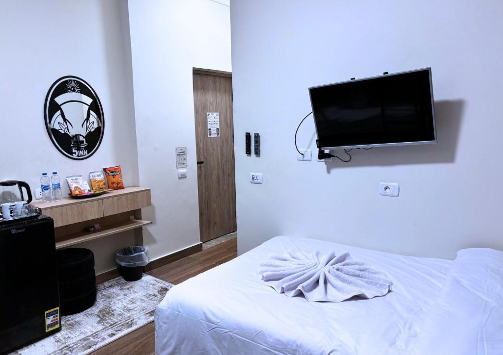 una camera da letto con un letto e una TV a schermo piatto di The 5 Inn - Pyramids a Il Cairo