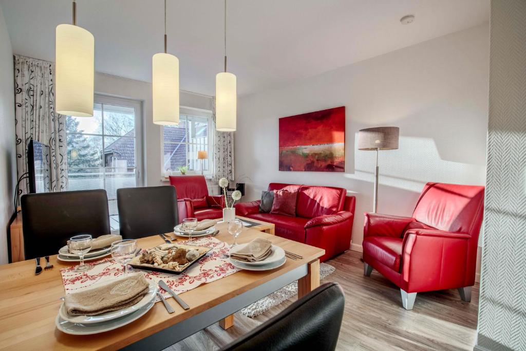 a living room with a dining table and red chairs at "Landhaus Voss" Typ 2 Nr8 in Staberdorf