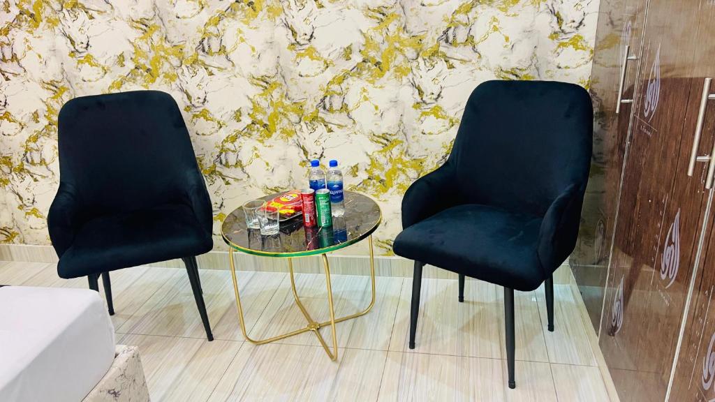 two black chairs sitting next to a glass table at Holiday Guest House Lahore in Lahore