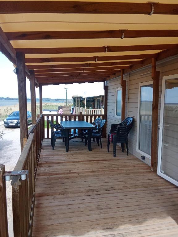 une terrasse en bois avec une table et des chaises dessus dans l'établissement Mobile home cosy 6 personnes!, à Canet