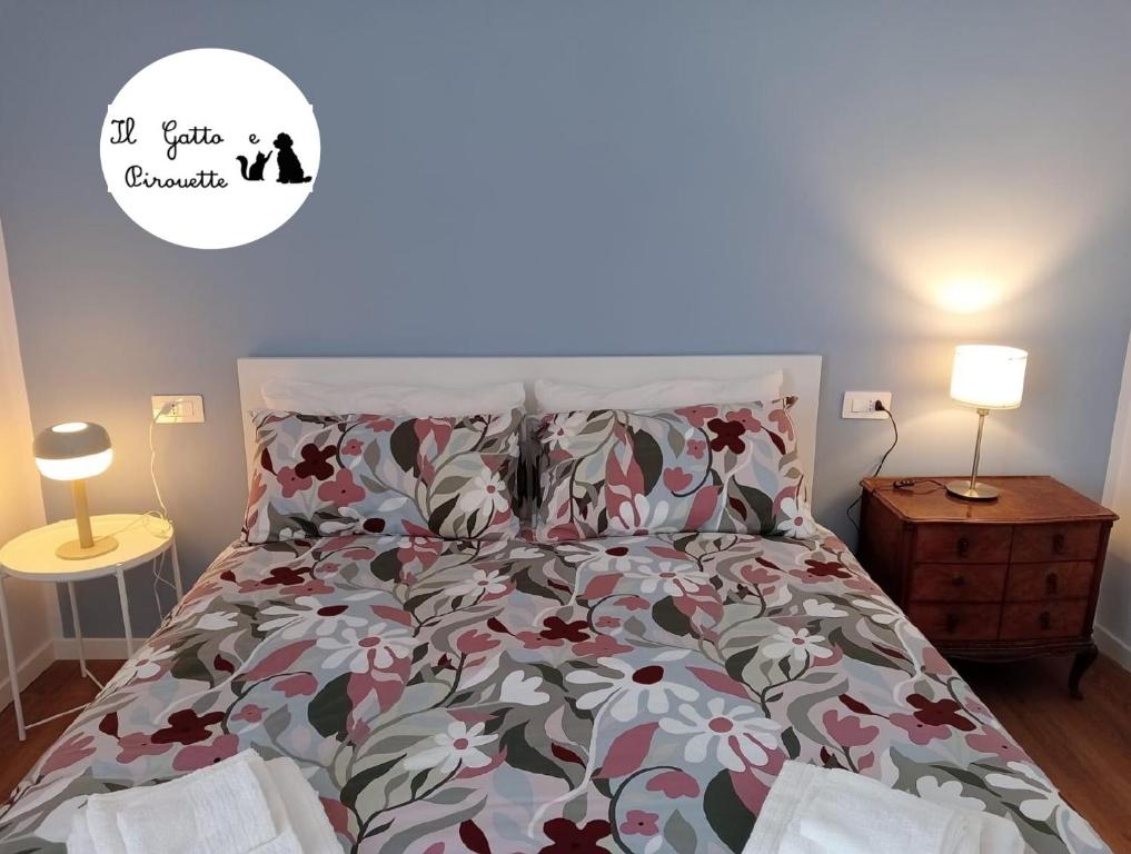 una camera da letto con un letto con copriletto floreale e 2 lampade; di Il Gatto e Pirouette a Napoli