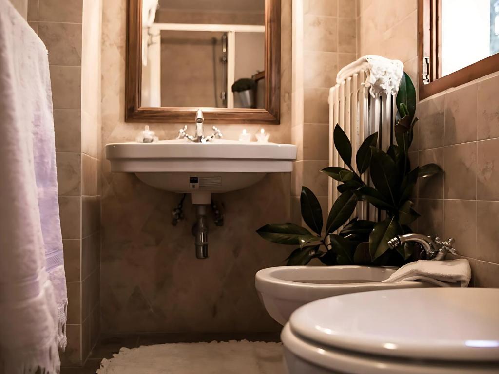 a bathroom with a sink and a toilet and a mirror at Locanda Il Pino in San Gimignano