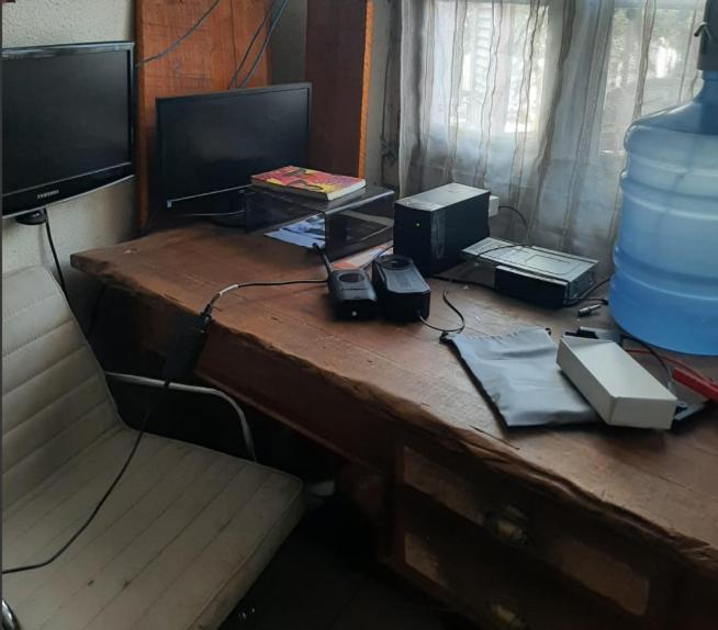 a desk with two monitors and other electronics on it at Cytau mesa de trabalho e sofá-cama com ar condicionado, café, wi-fi e água liberados, acesso fácil in Porto Alegre
