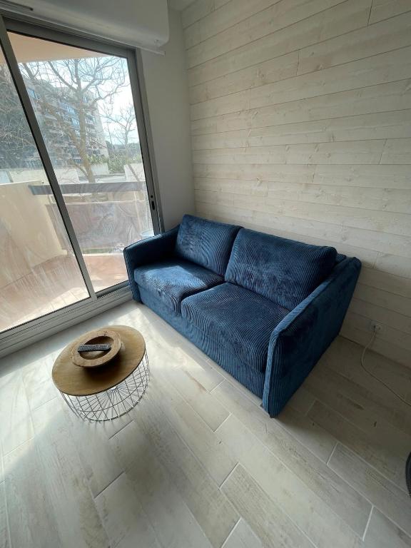 un salon avec un canapé bleu et une table dans l'établissement Appartement au pied du port, à Canet